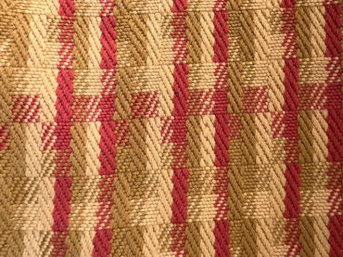 Vue rapprochée sur le motif géométrique du tissage artisanal aux nuances or et brique.
