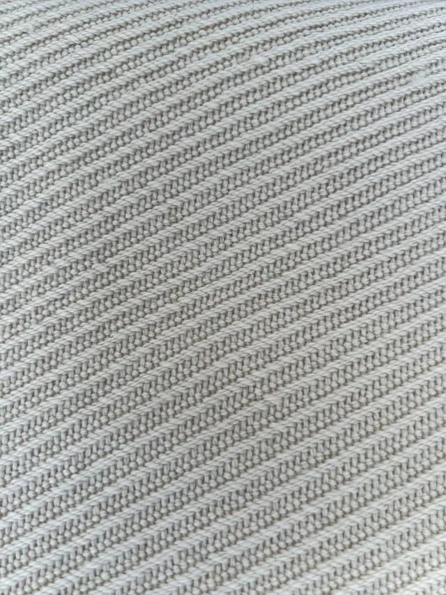 Gros plan sur le tissage texturé aux motifs obliques d'une écharpe couleur champagne.