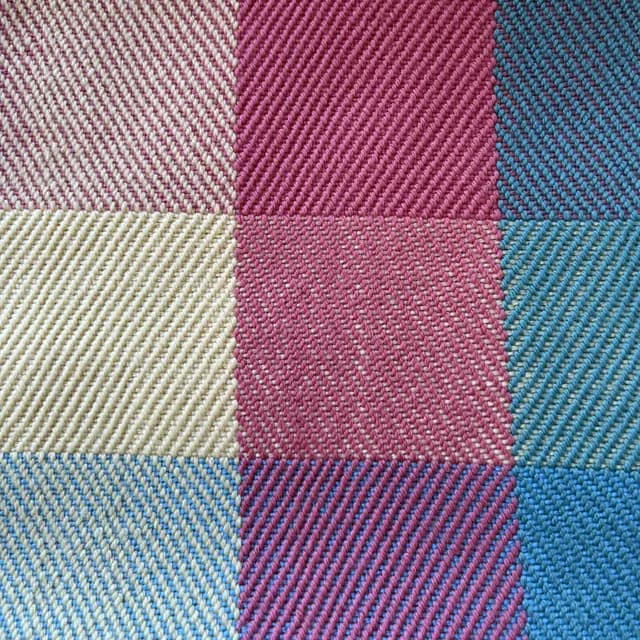 Détail du tissage sergé artisanal aux mailles roses, bleues et écrues.