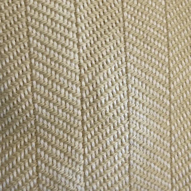 Gros plan sur la texture du tissage artisanal à motif chevron dans les tons champagne et blanc.