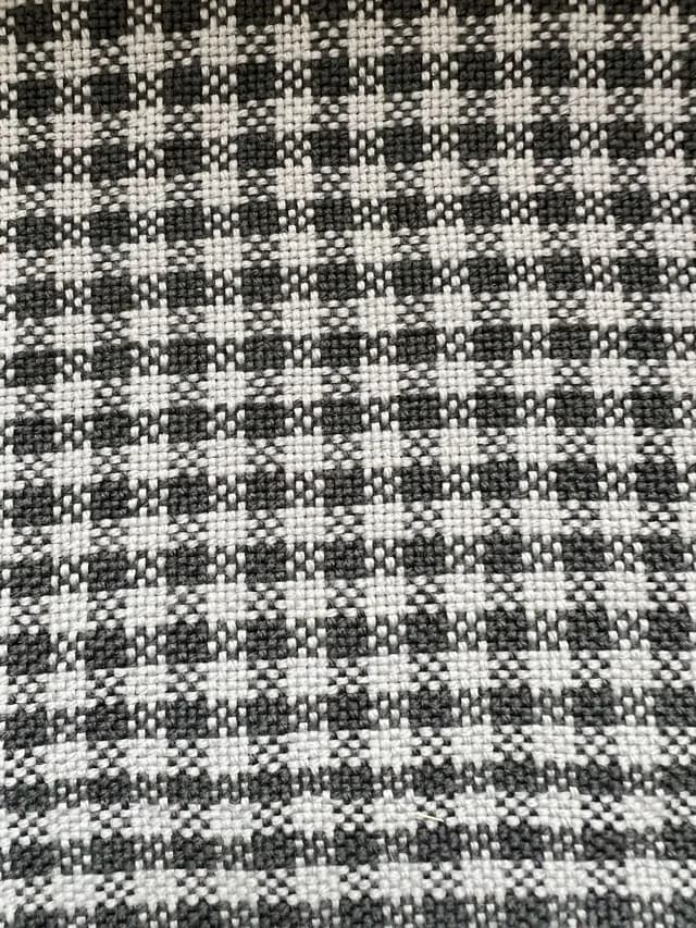 Gros plan sur le tissage artisanal en laine à motif de petits carreaux noirs et blancs.