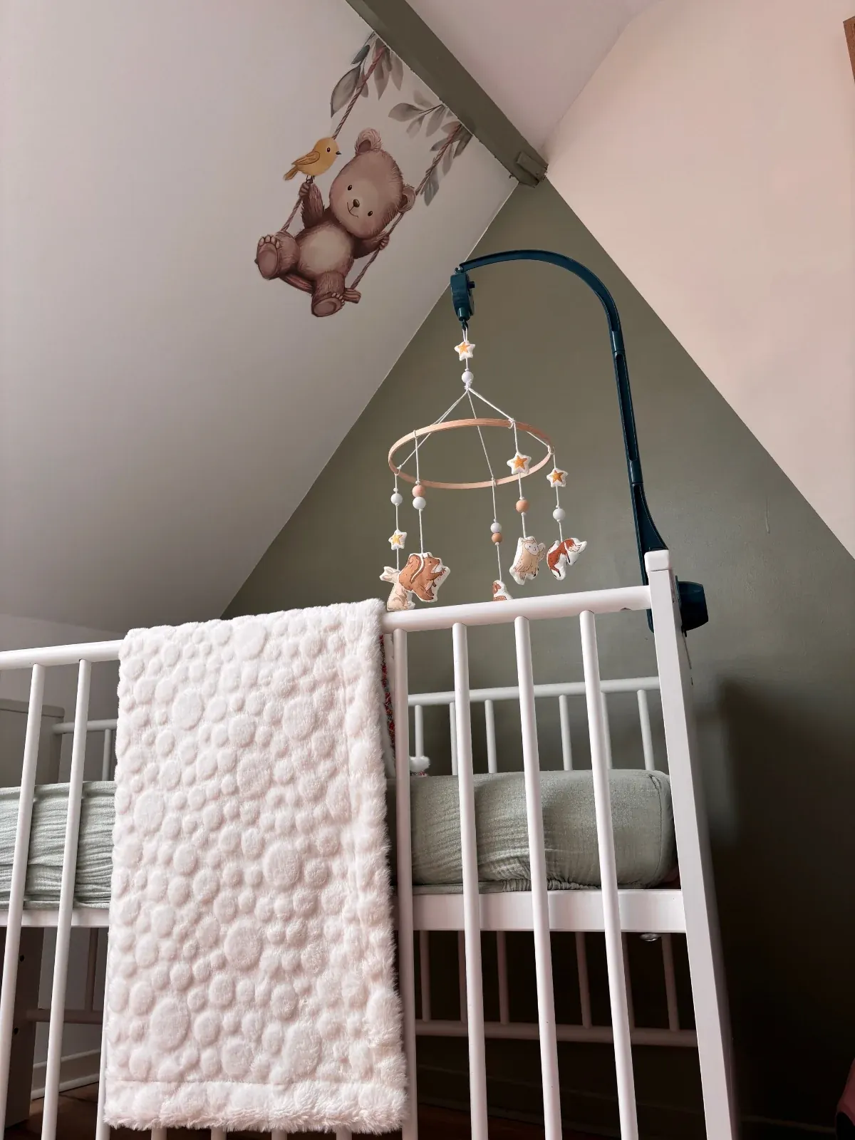 Face en polaire texturée blanche de la couverture pour bébé, drapée sur la barrière d'un lit à barreaux.