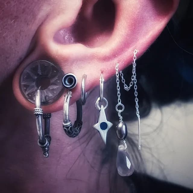 Chaînette d'oreille portée sur une oreille percée avec d'autres bijoux en argent.