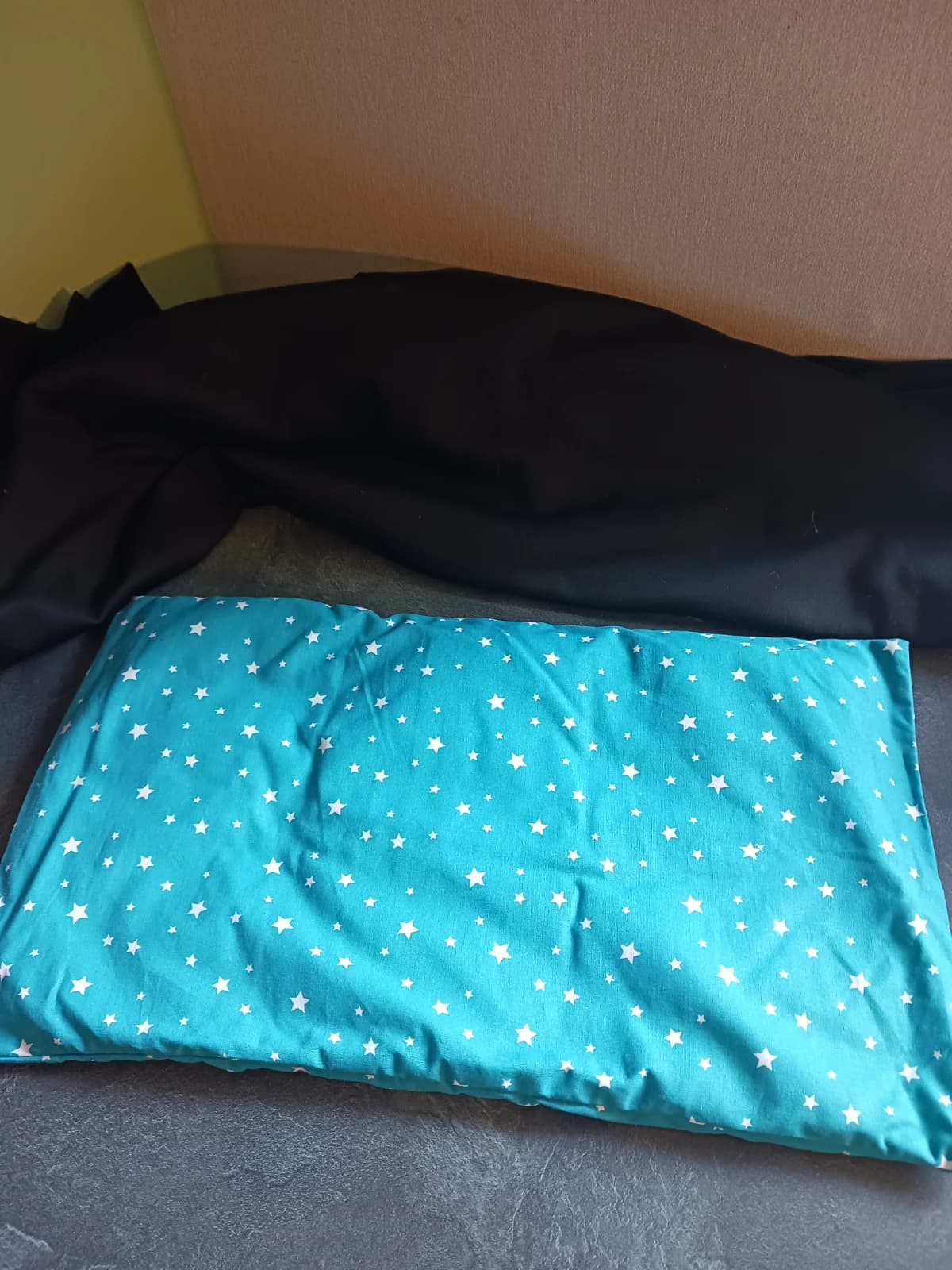 Bouillotte coussin rectangulaire en tissu turquoise ornée d'étoiles blanches.