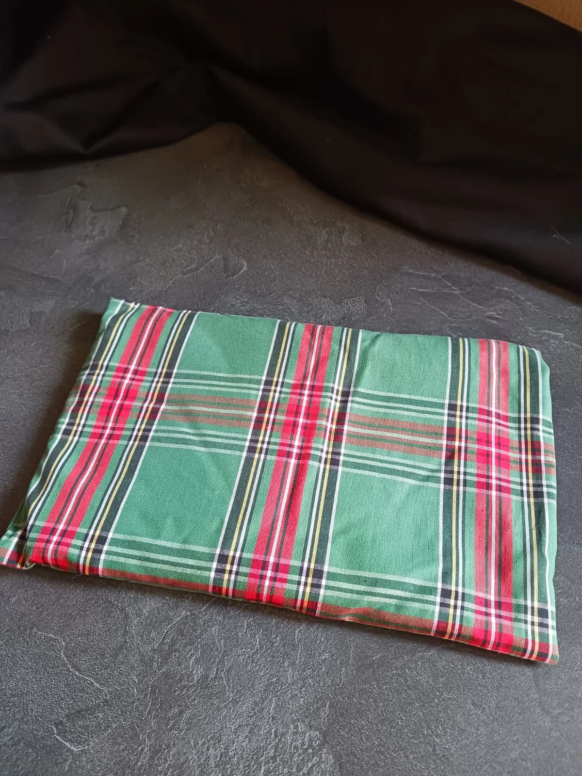 Coussin rectangulaire en tissu à motif tartan vert, rouge et jaune posé à plat.